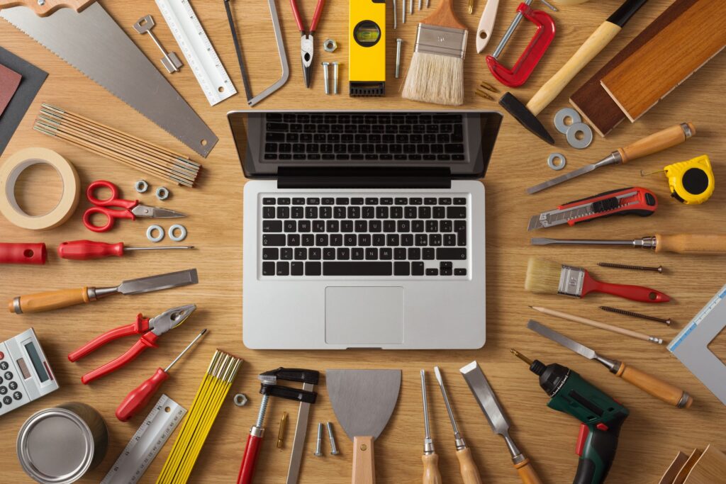 Laptop on a workbench surrounded by DIY and construction tools, top view, hobby and crafting concept