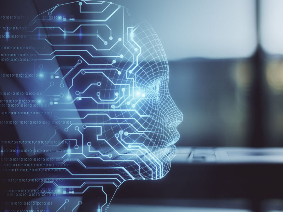 A side profile of a human head formed by glowing blue lines and circuit-like patterns, suggesting a digital or artificial intelligence representation. The face appears semi-transparent and geometric, with interconnected nodes and pathways extending outward. Binary code is faintly visible on the left side, while a blurred laptop sits in the background, reinforcing a technology-focused setting.