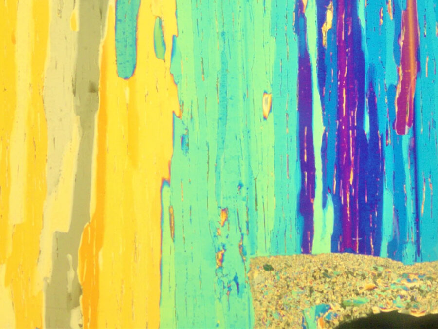 This image shows long vertical streaks in bright yellow, turquoise, blue, and purple. The layered colors and textured lines resemble dripping paint or weathered wood grain, creating a vivid, striped pattern across the image.